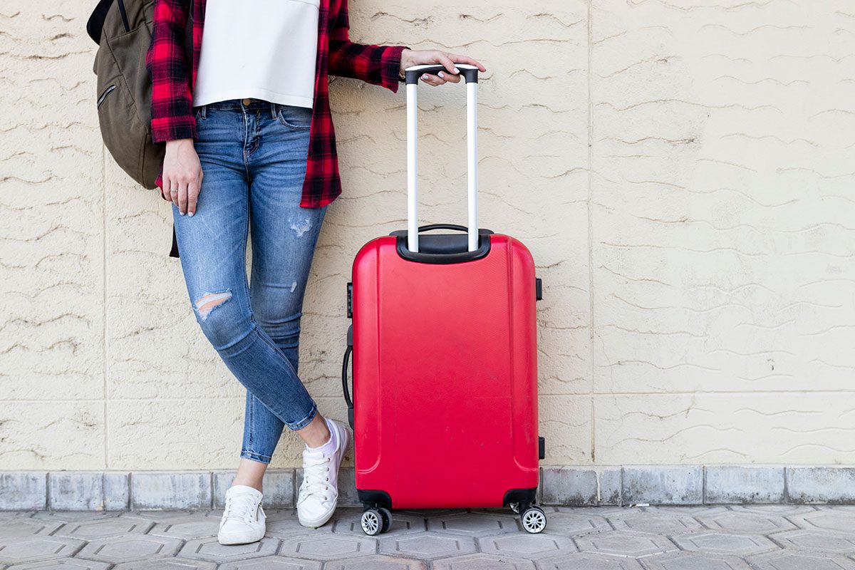 Woman standing by a wall with suitcase