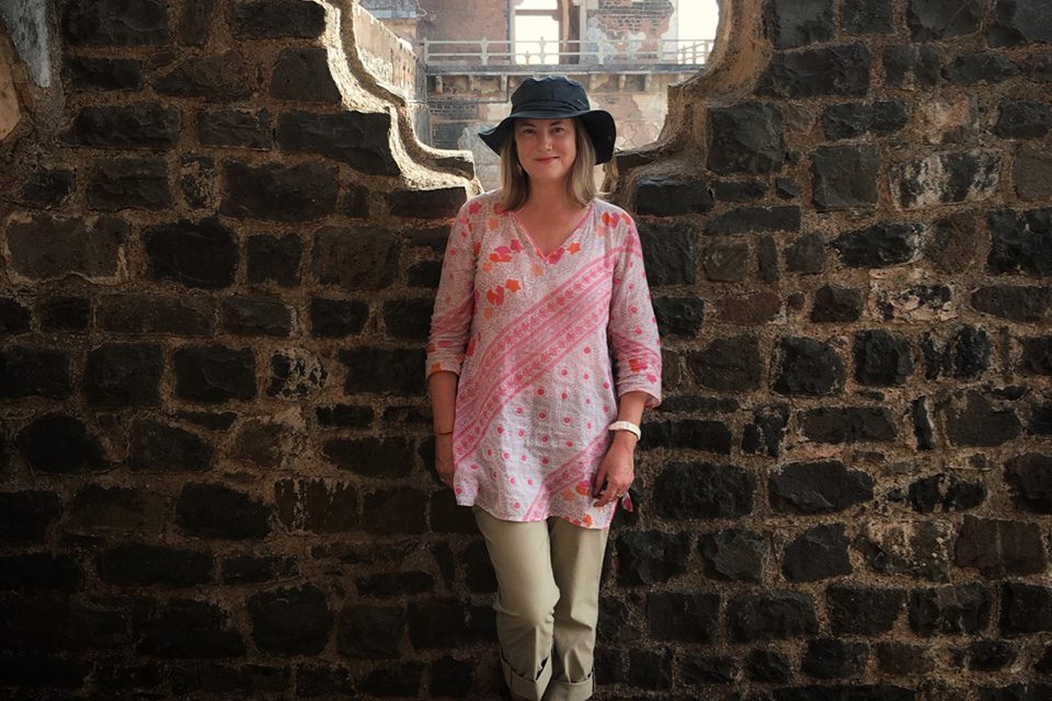 Woman in a pink shirt standing against a wall, travelling solo in india