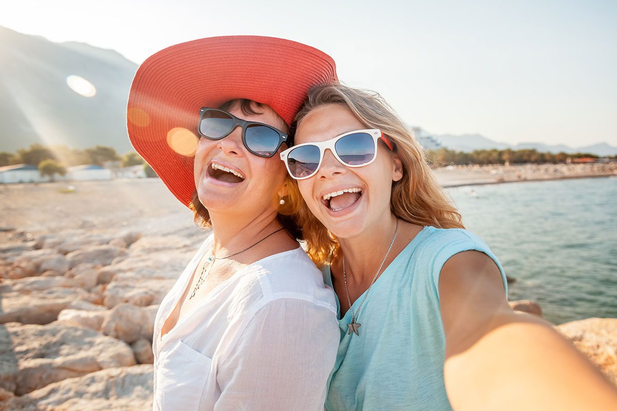 Mother and daughter taking selfie on the beach