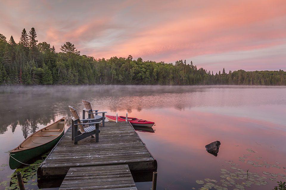 Muskoka chairs and lake at sunset glamping in Muskoka