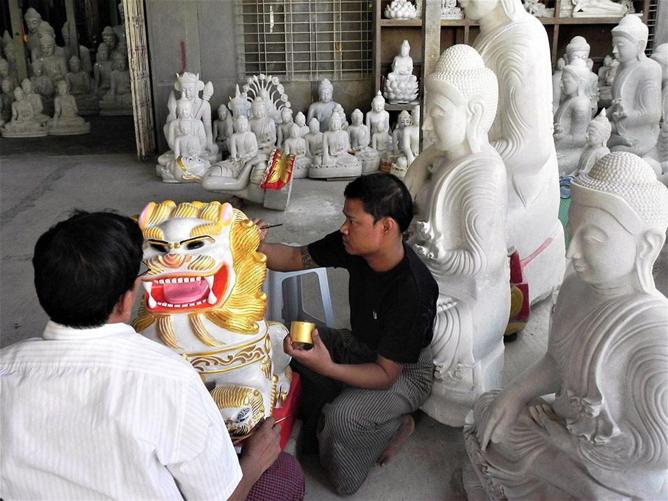 Two men paint sculptures in Burma