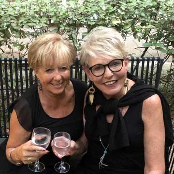 Two smiling women hold wine glasses