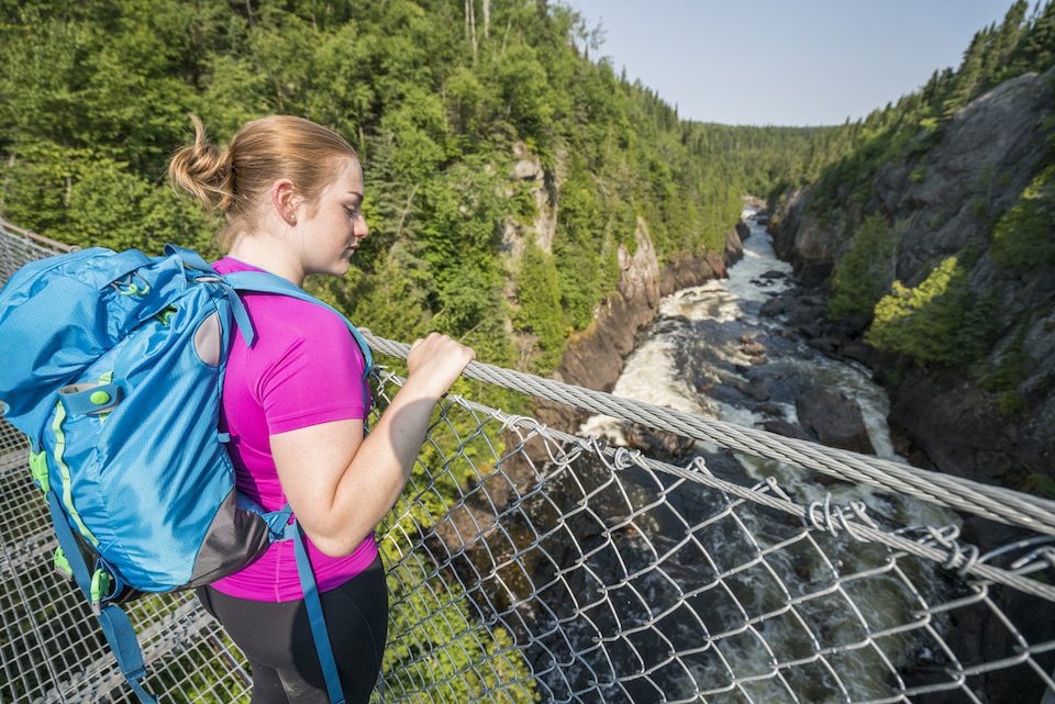 Visitor enjoying the views of the White River Suspension bridge high above Chigamiwinigum Falls. Pukaskwa National Park