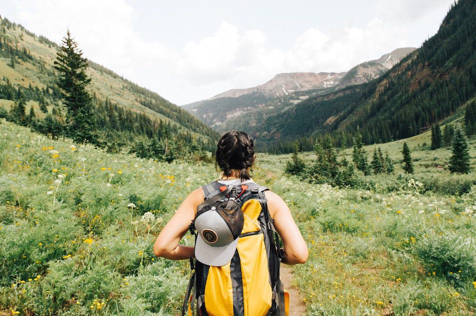 A solo woman hiker overlooks the mountains in Crested Butte enjoying slow travel