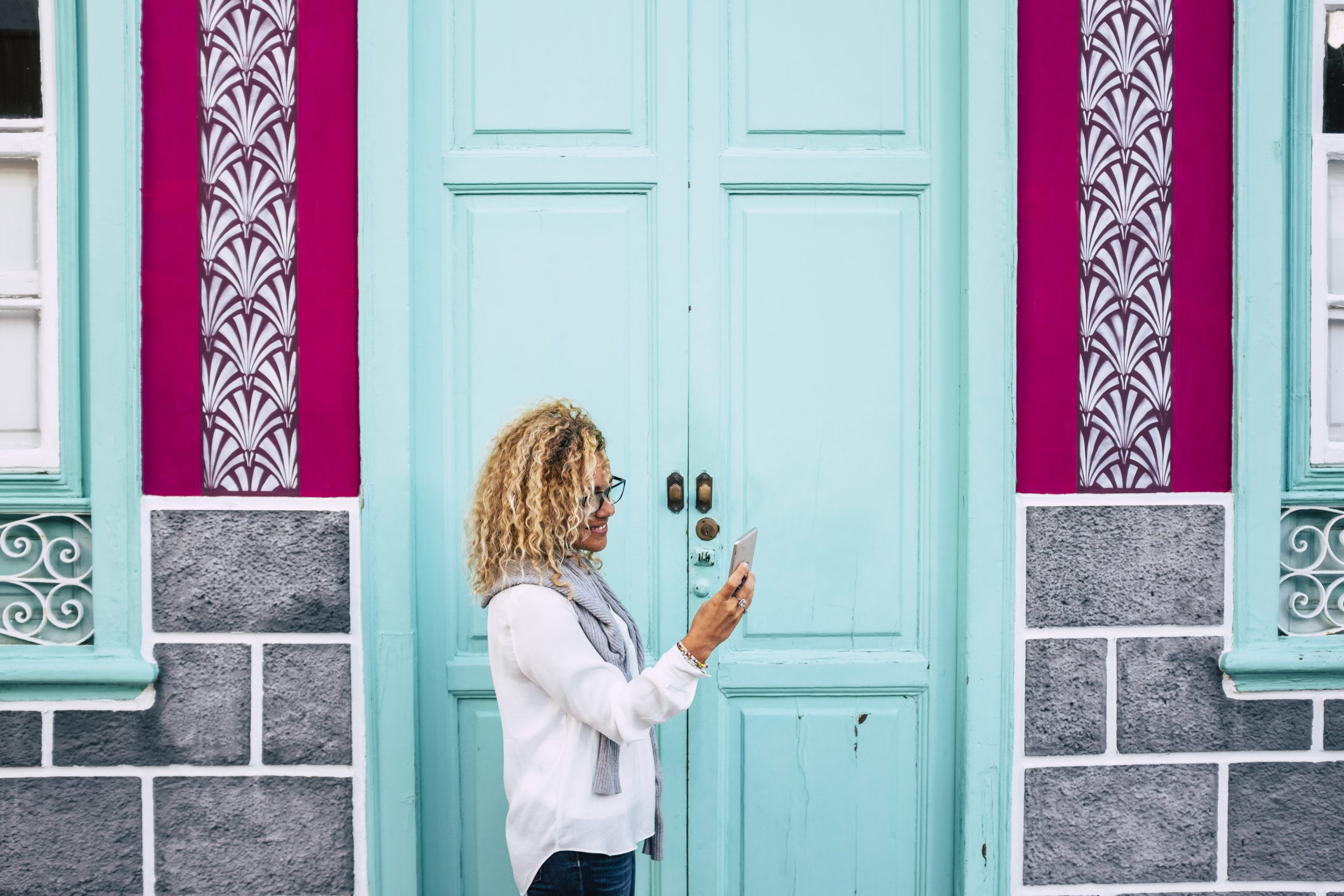 Adult woman outside a coloured house do a phone call with cellul