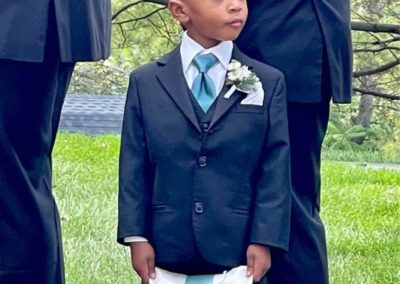 A young boy wearing a suit and holding a decorative pillow