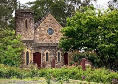An old stone house sits surrounded by lush greenery