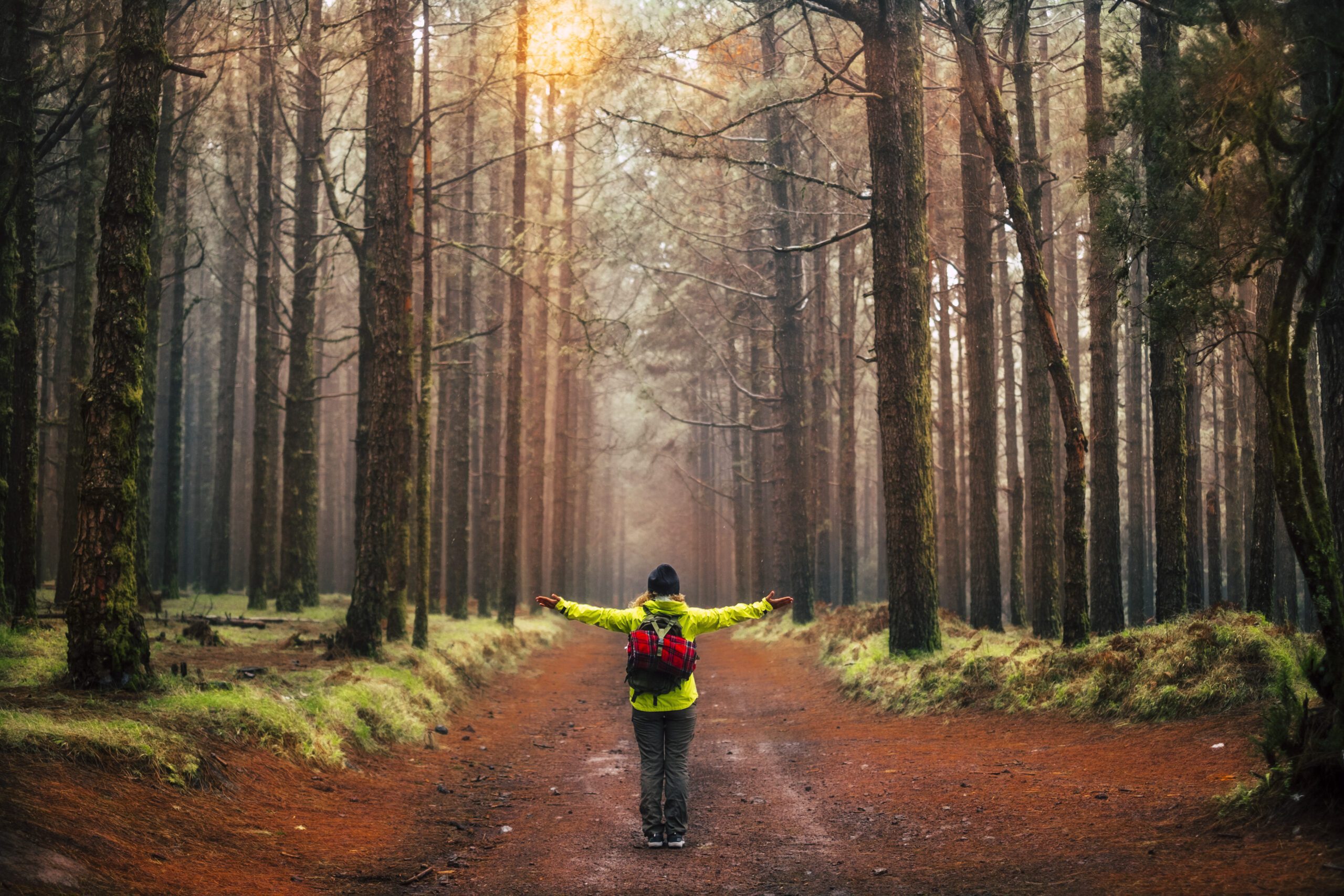 Woman hiking through a forest with her arms out at her side