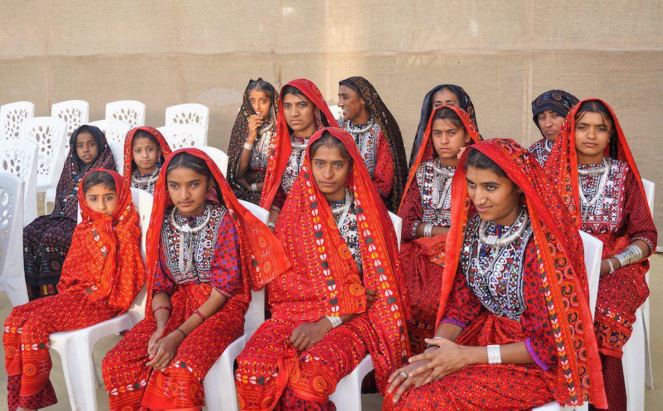 Young women wearing traditional red embroidered dress from the Gujarat 