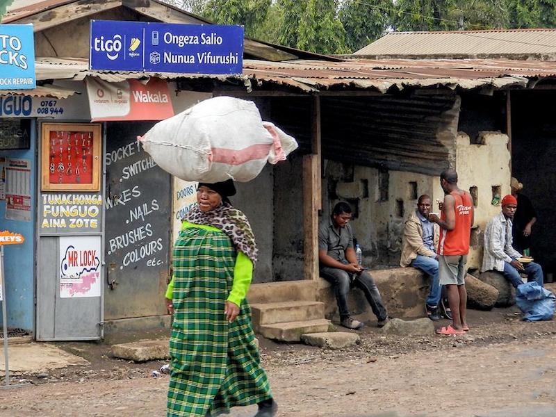 Woman with load on her head as men sit