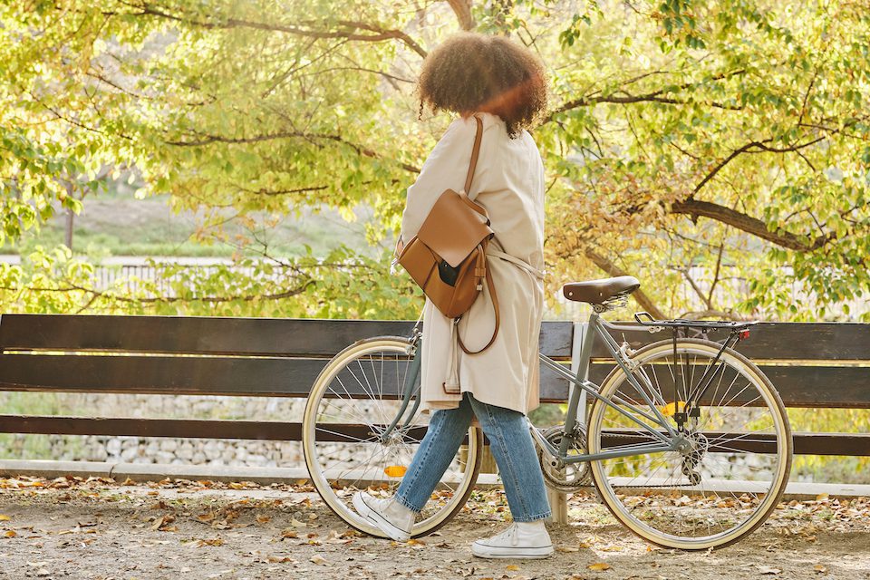 Woman walking with her bike through a park on an autumn day