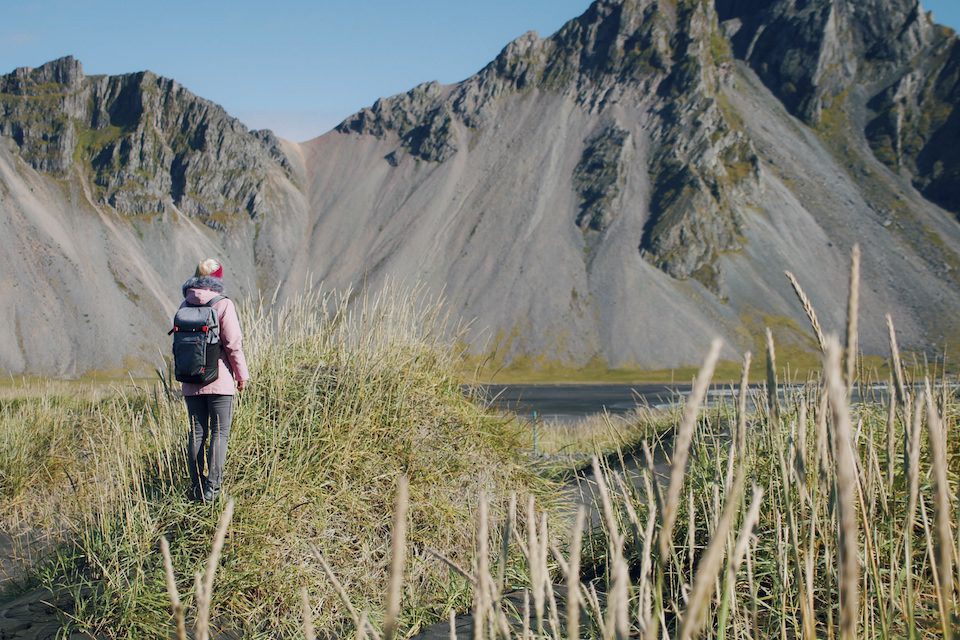 Woman Iceland adventure outdoor trip to Stokksnes black beach Vestrahorn mountain in the background Nature and travel concept.