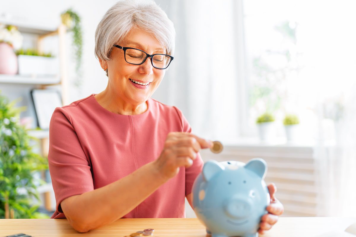 Woman adding coins to piggy bank to save money on travel
