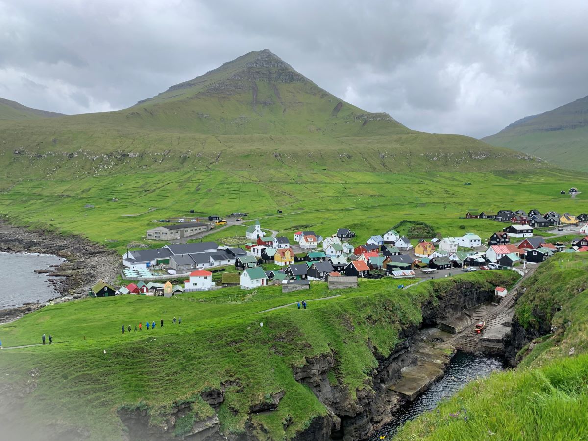 green hill with houses in the distance