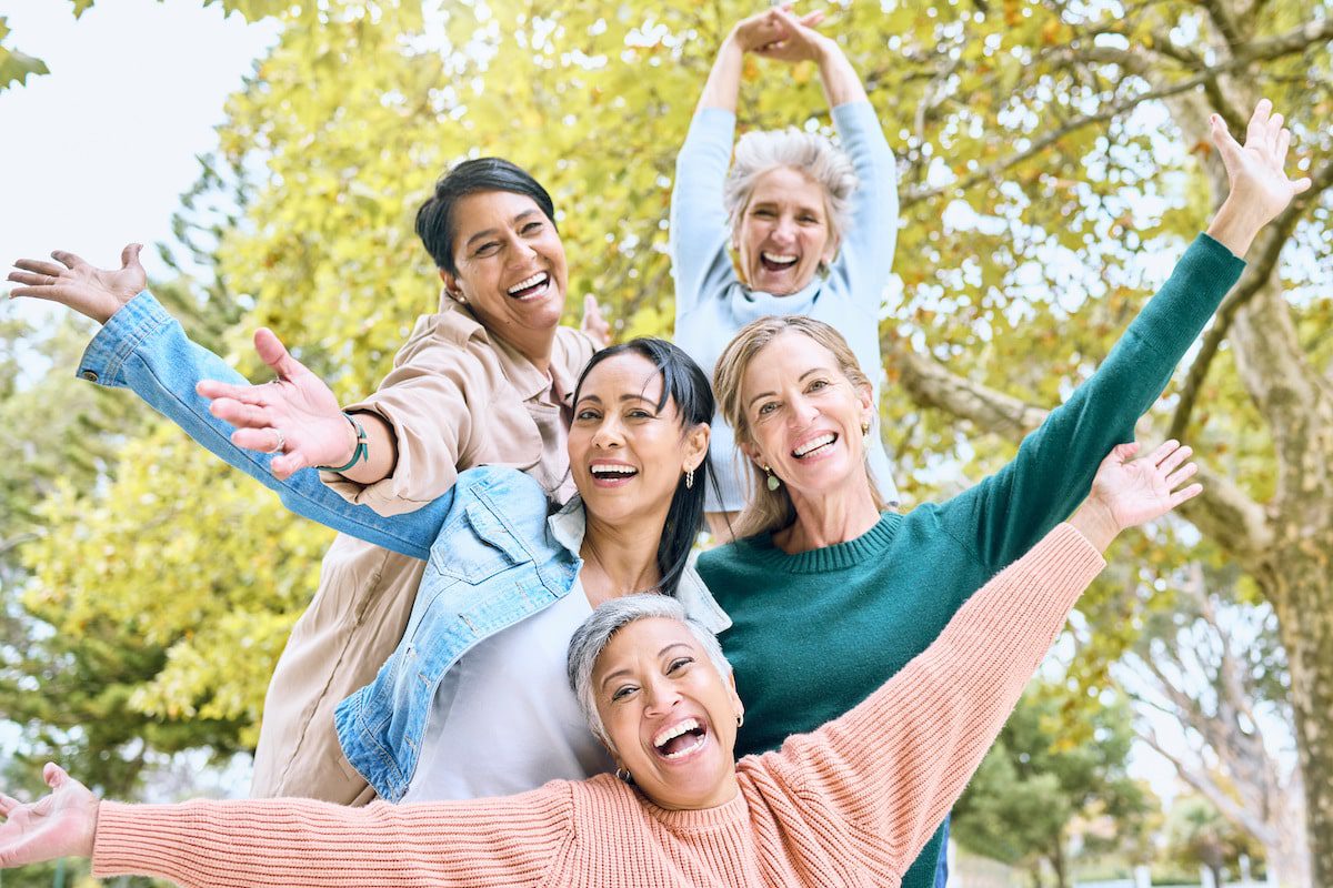 A group of women smile and pose together outdoors