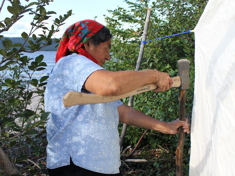 Mrs P secures the tent with poles she and Frances have cut in the forest.