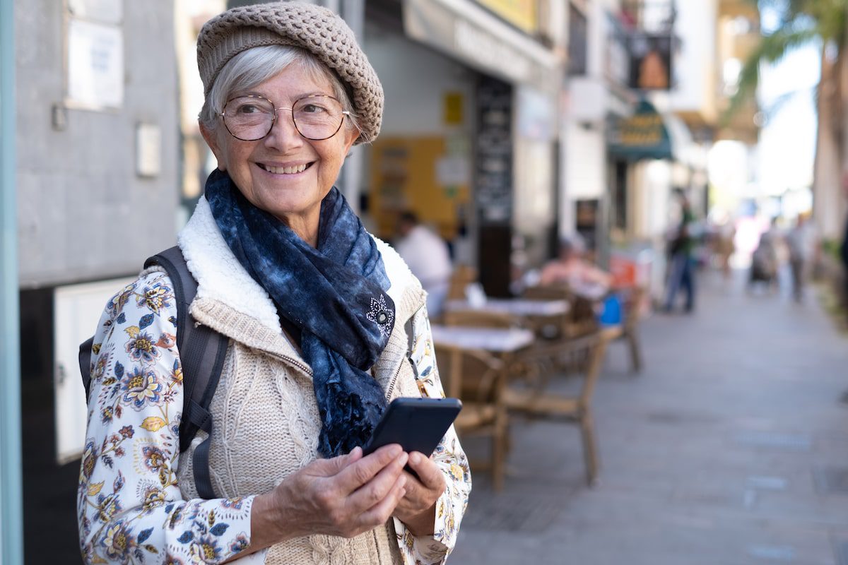 A woman holds her cell phone while traveling overseas with an eSIM card.
