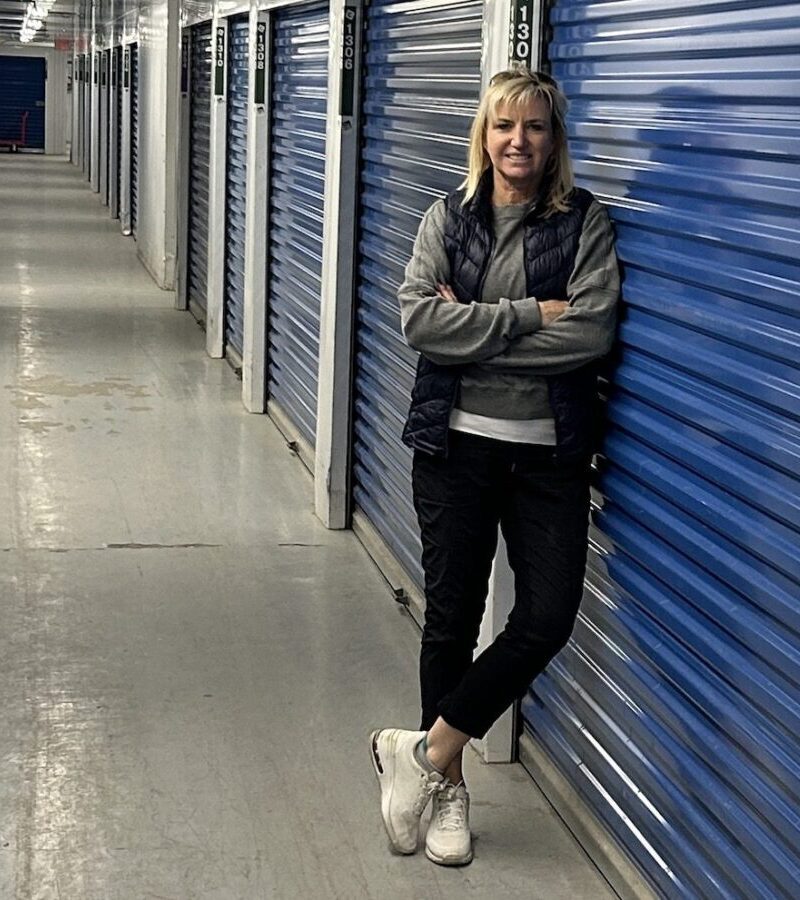 Carolyn Ray stands in front of her storage locker after downsizing for travel.