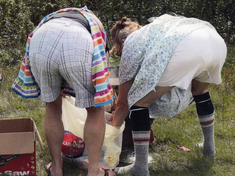 Two people bent over foraging in the woods