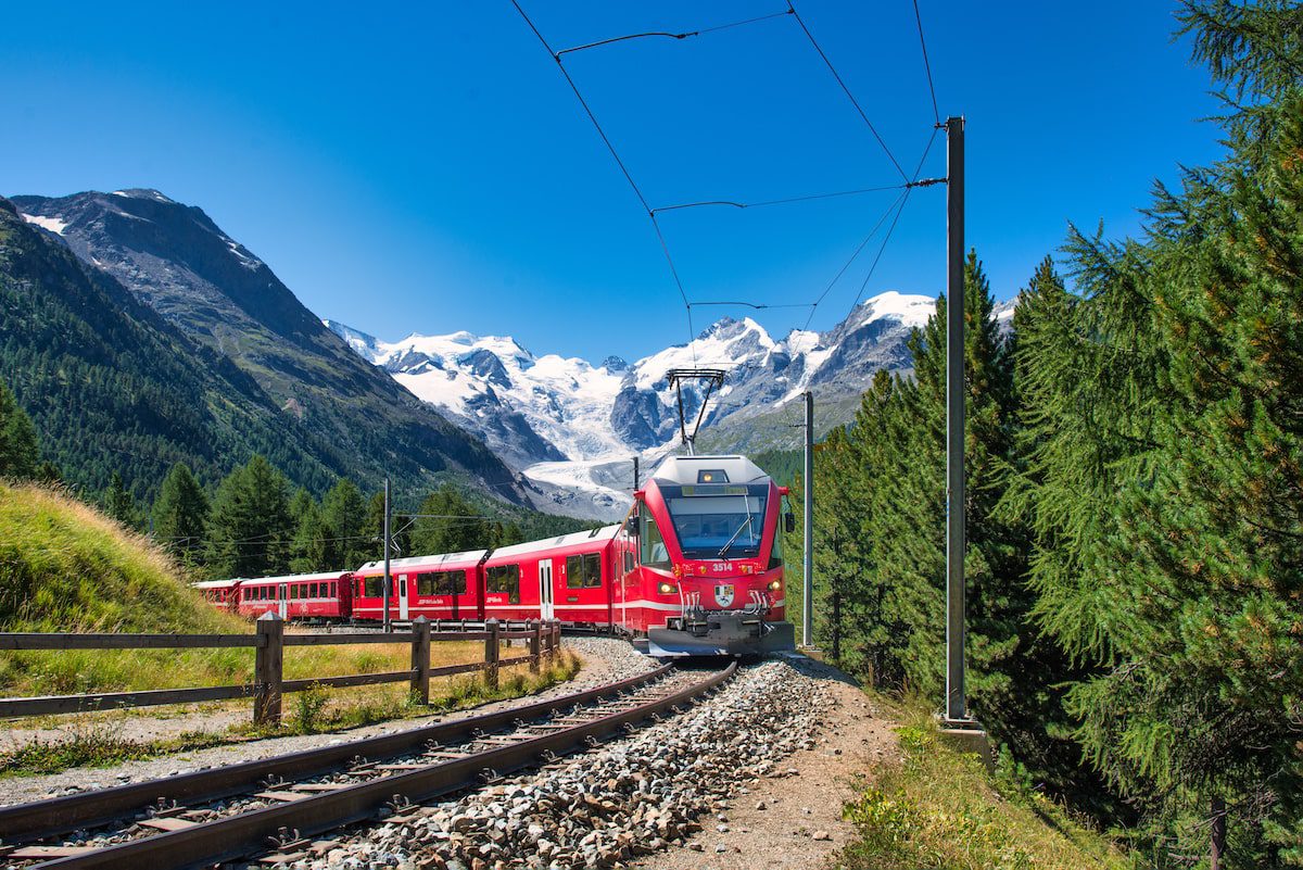Famous Bernina tourist train passing under the glaciers of the Swiss Alps