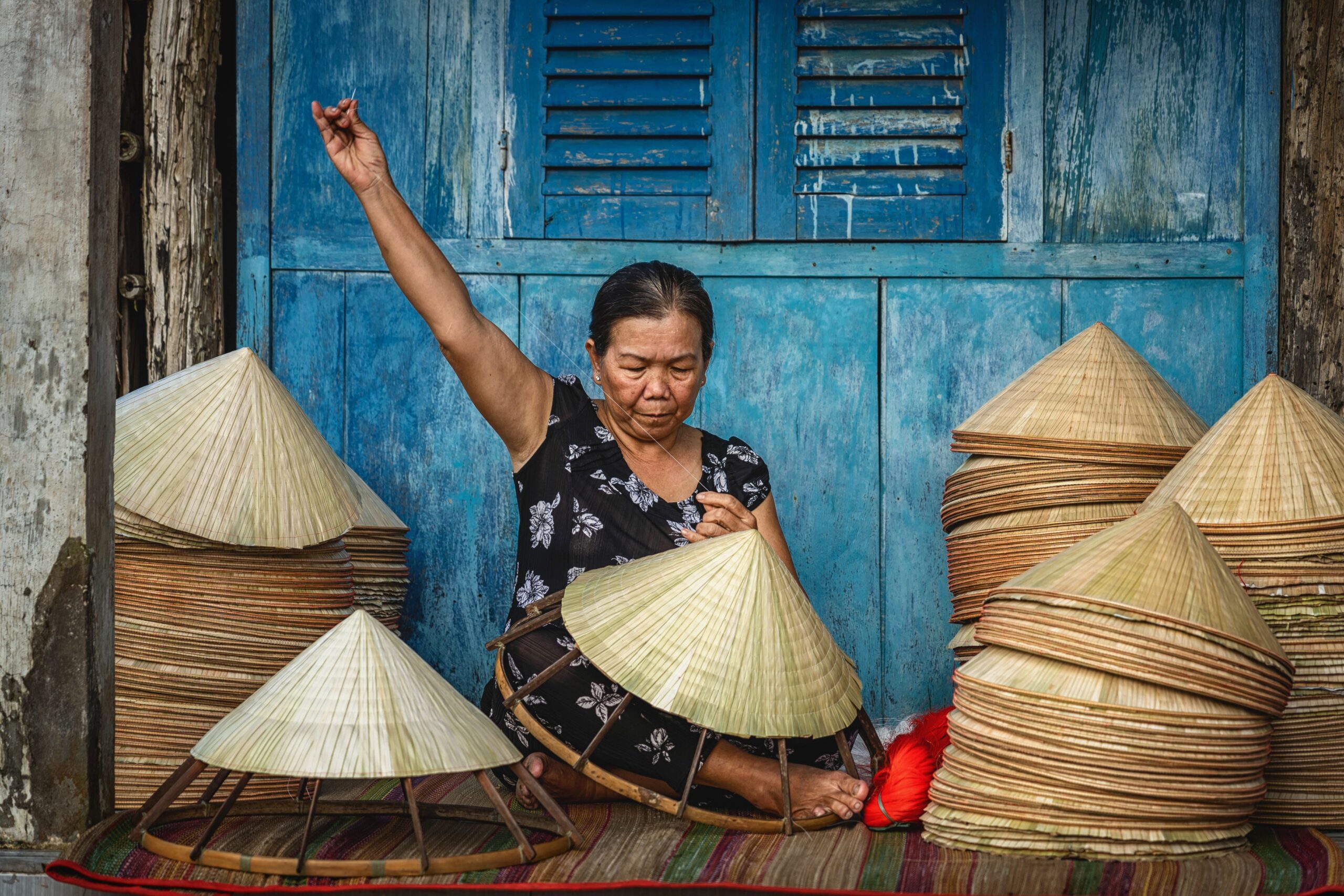 Woman sewing hat in Vietnam where the novel Dust Child is set