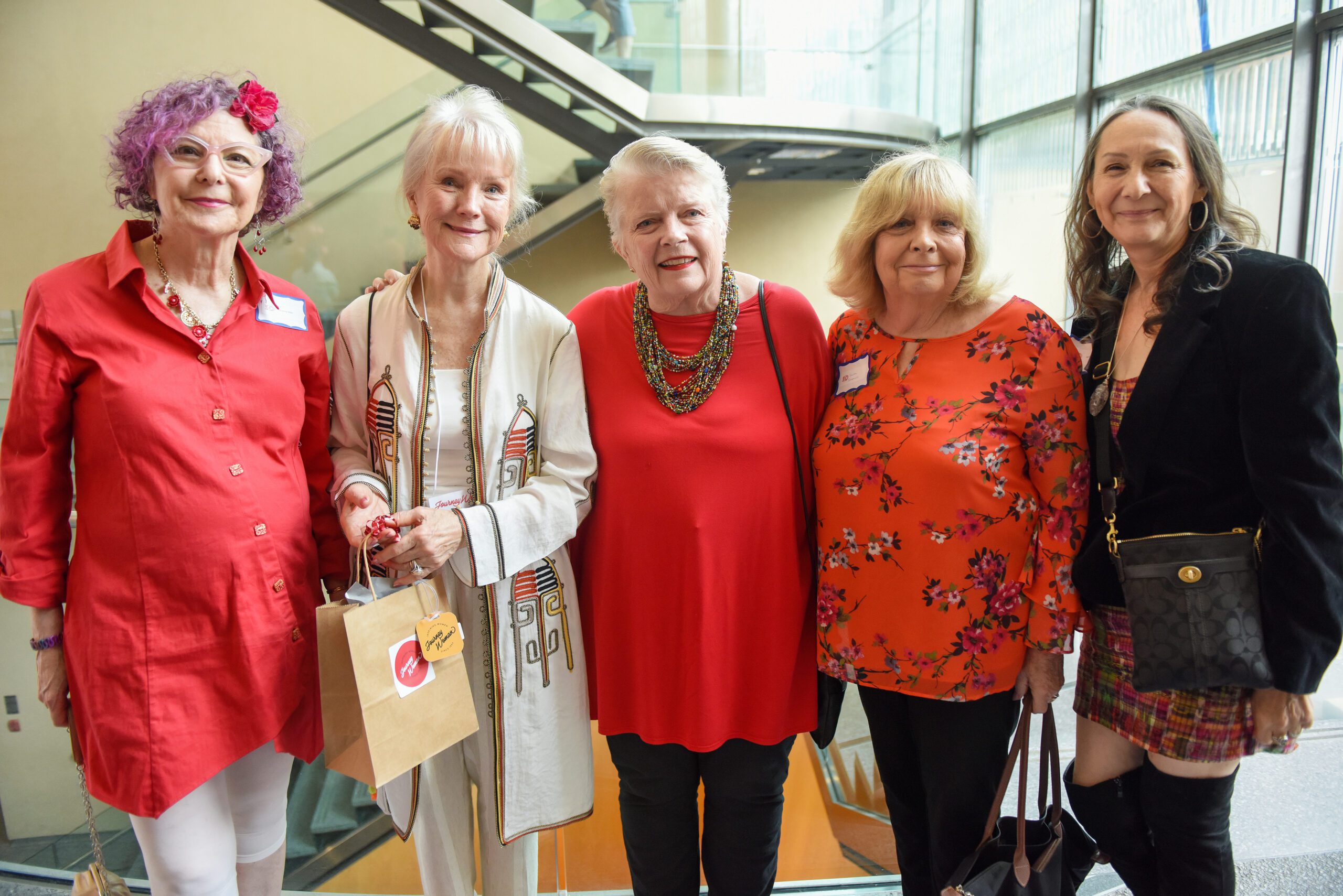 five women smiling at event wearing red