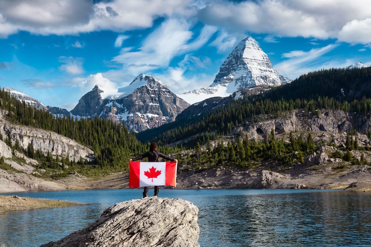 Girl Holding a Canadian National Flag. View of Og Lake in the Iconic Mt Assiniboine Provincial Park near Banff, Alberta, Canada. Mountain Landscape