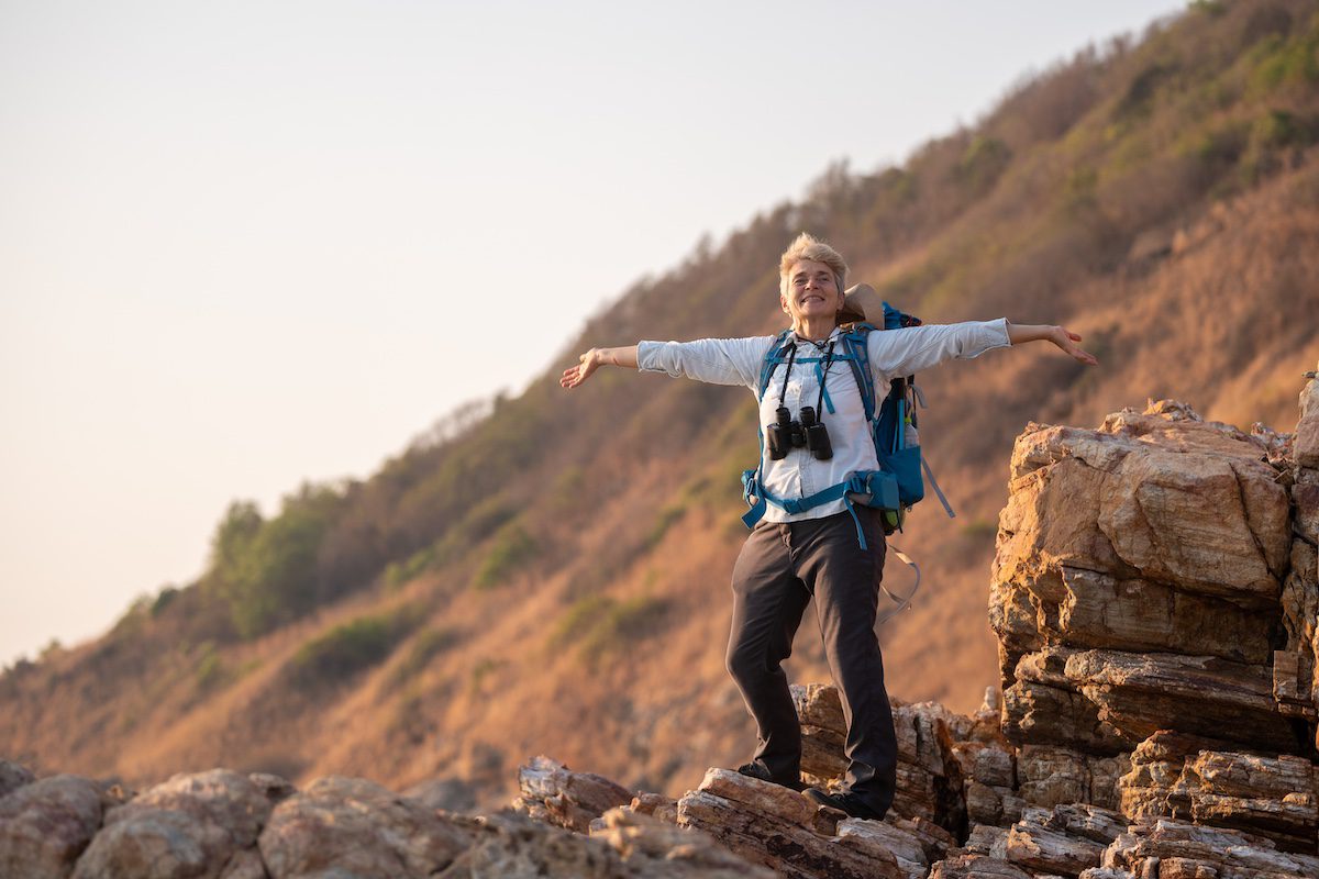Senior woman is hiking outdoors on an adventure trip in the mountains.