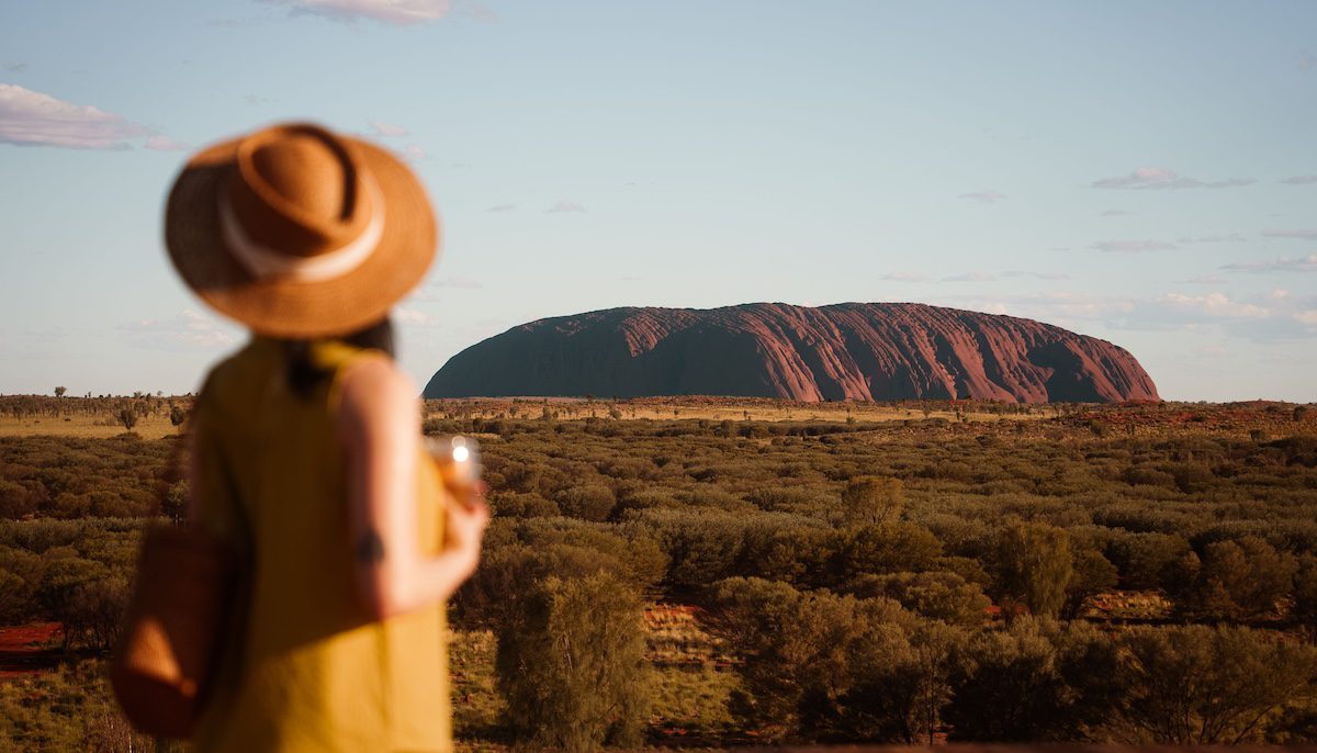 A woman overlooking Uluru in the background in Australia's Northern Territory