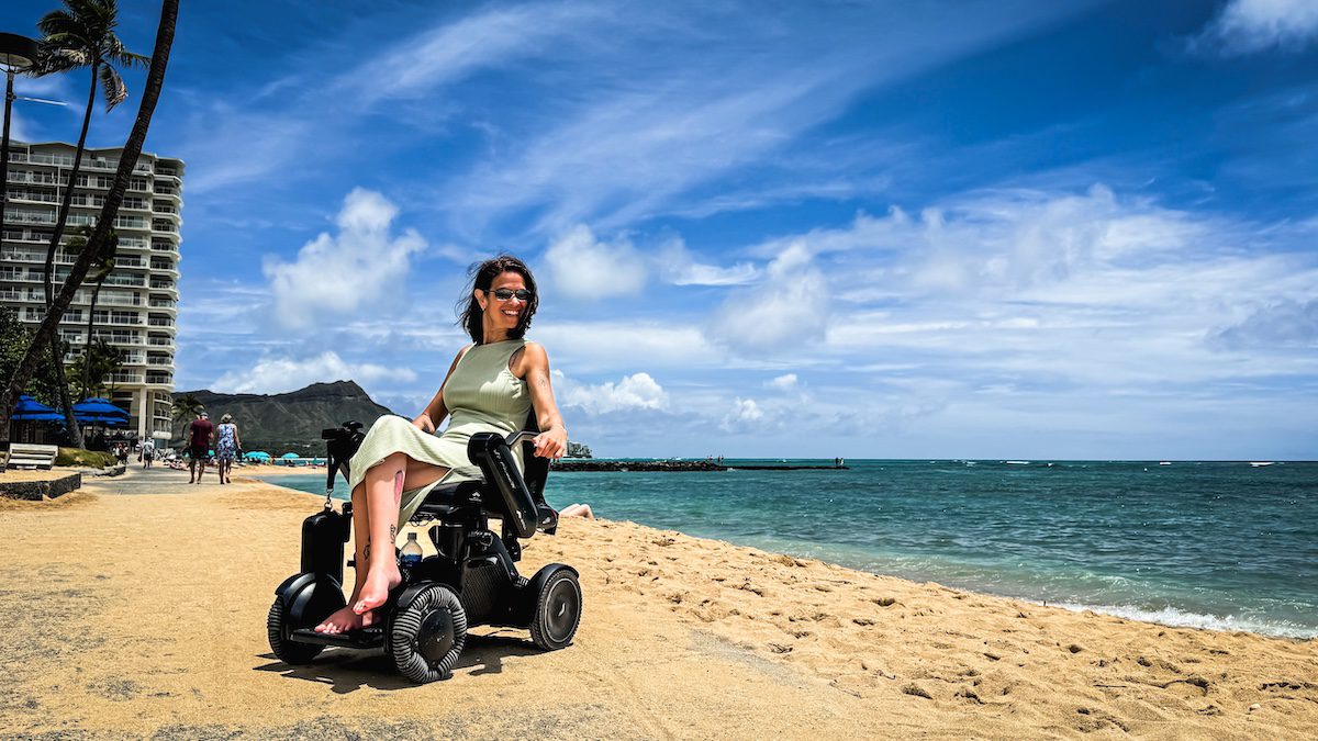 Sylvia Longmuire on a beach in her wheelchair travelling with MS