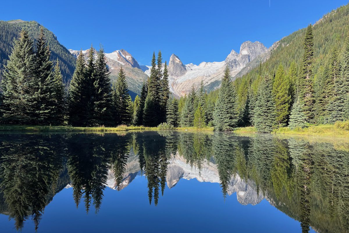 The Bugaboos reflect on a peaceful alpine morning